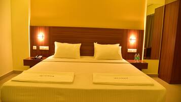 A hotel room with a large bed, two bedside tables, and a mirror.