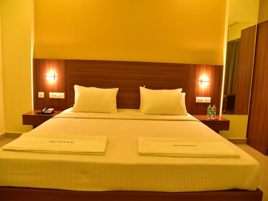 A hotel room with a large bed, two bedside tables, and a mirror.