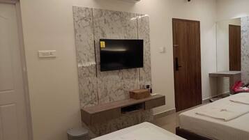 A hotel room with a marble wall, a flat-screen TV, a wooden cabinet, a wooden door, and two beds with white linens.