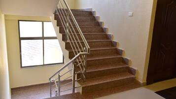 A staircase with a metal railing, carpeted steps, and a window on the left.