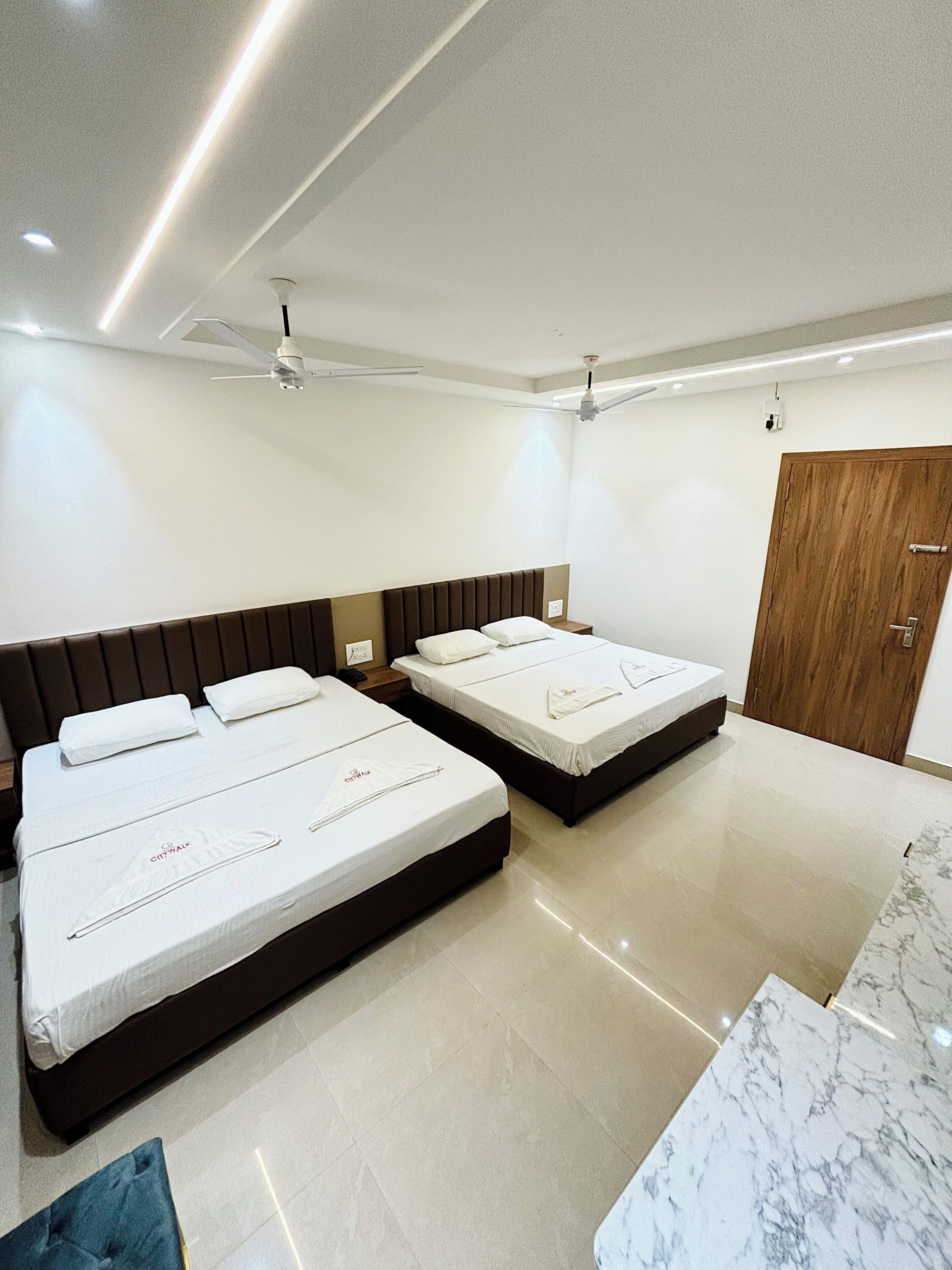 Una habitación de hotel con dos camas, un armario de madera y suelo de baldosas de mármol.