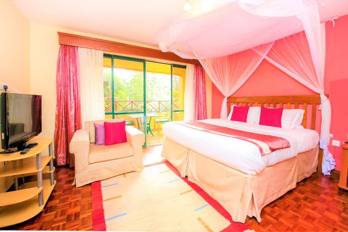 Een slaapkamer met een bed, een televisie, een bank en een balkon.