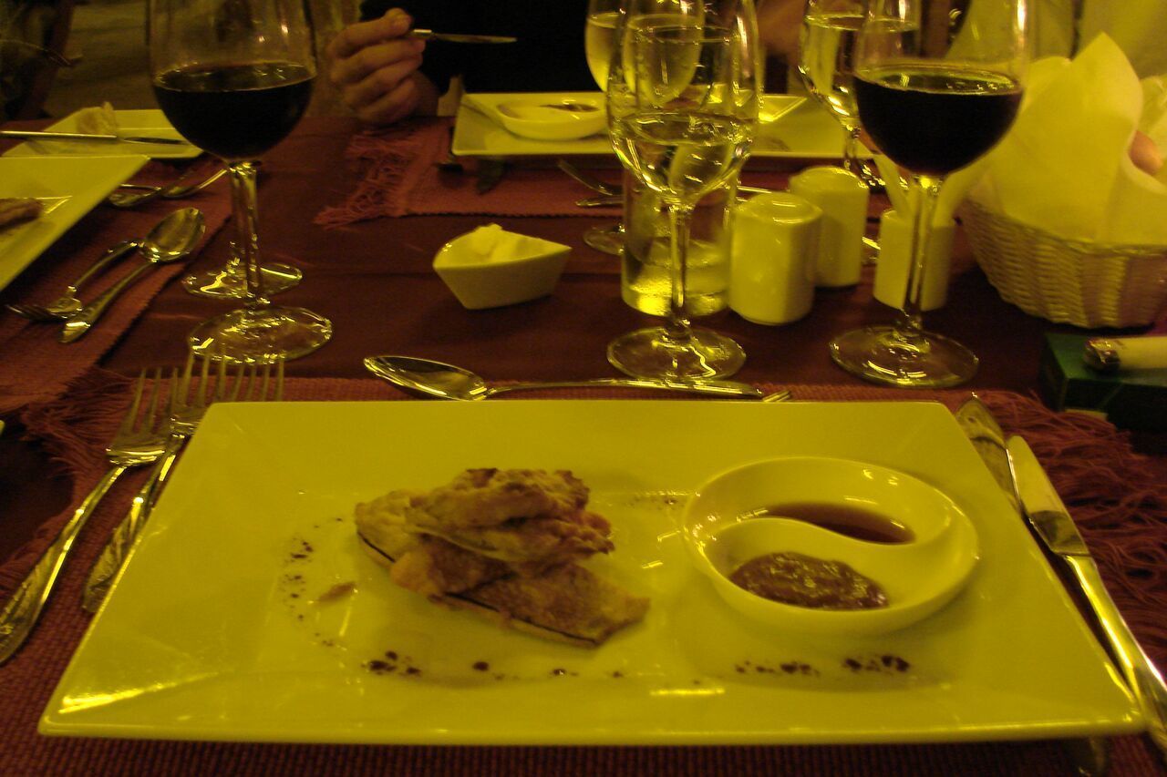 Una mesa de comedor con platos, cubiertos y copas de vino.