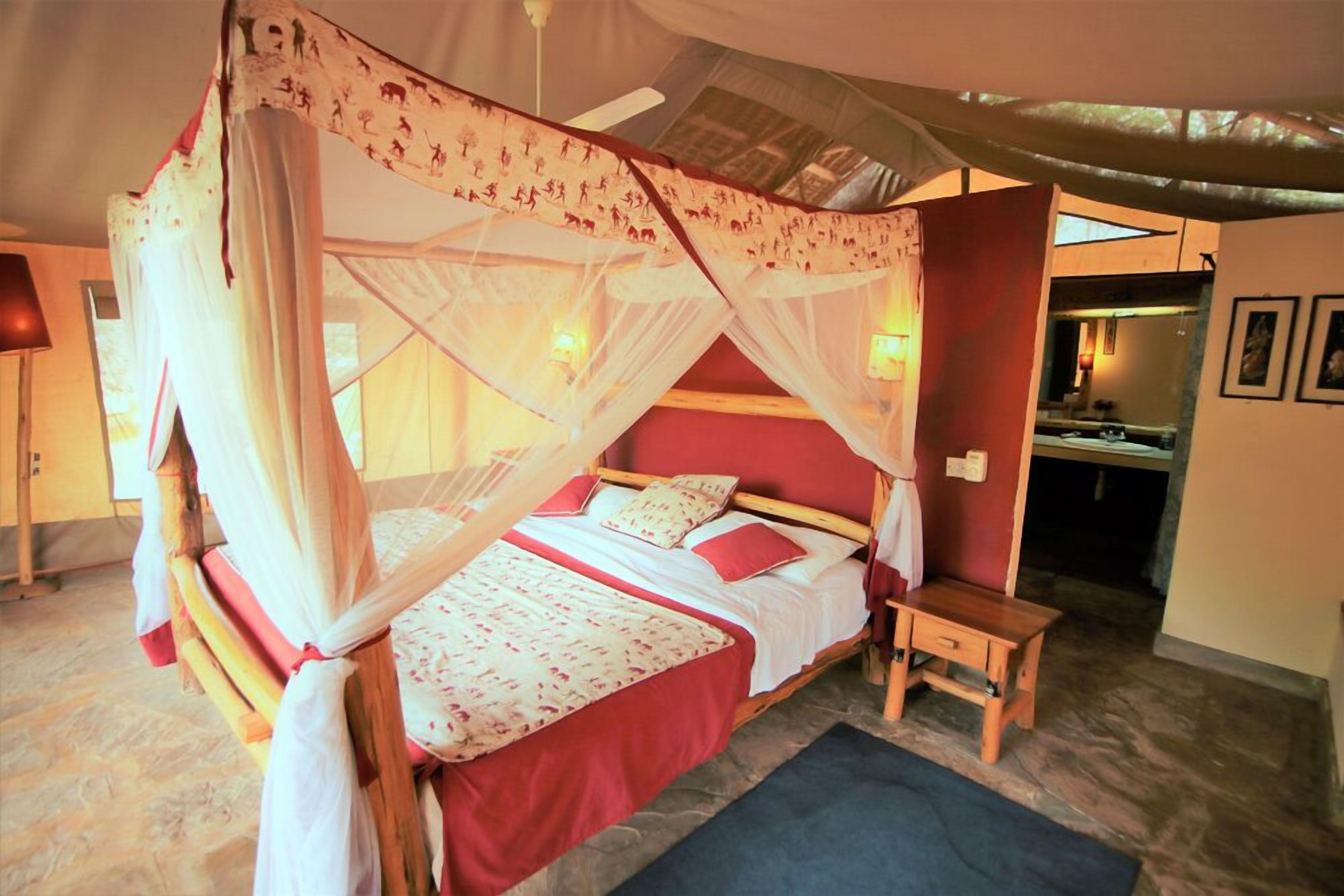 Un dormitorio con una cama con dosel, una mesita de noche y un pequeño mueble auxiliar.
