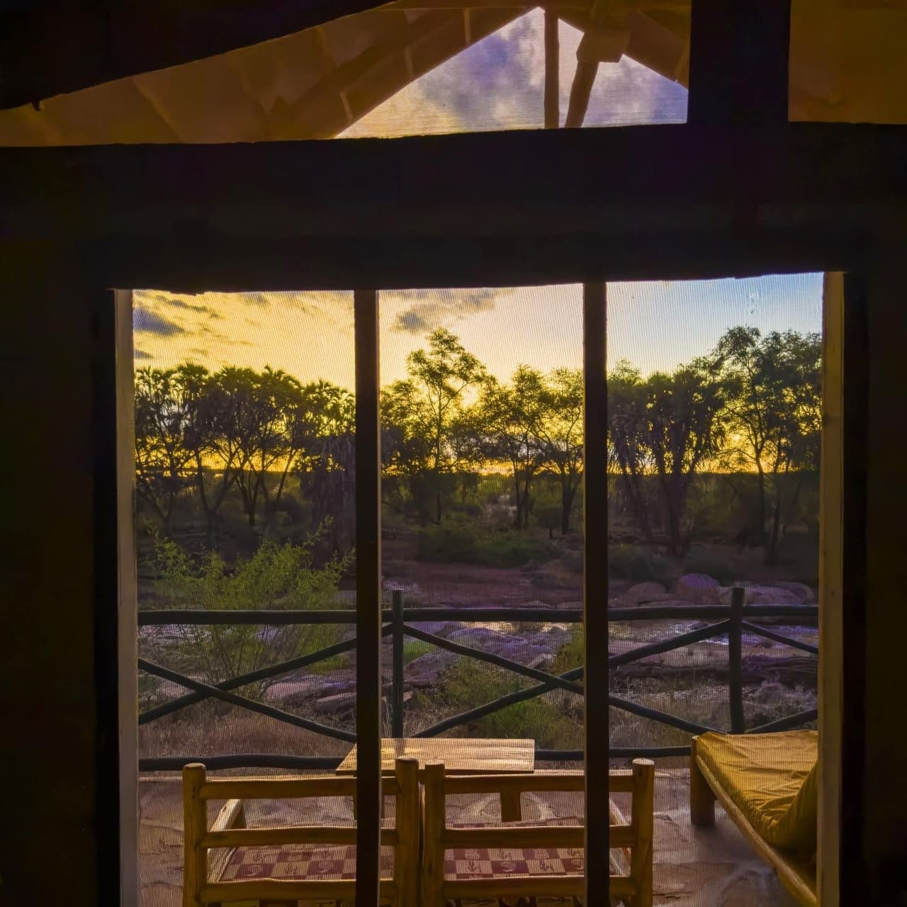 Una habitación con un ventanal grande que da a un paisaje natural con árboles y cielo despejado.