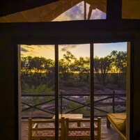 Una habitación con un ventanal grande que da a un paisaje natural con árboles y cielo despejado.