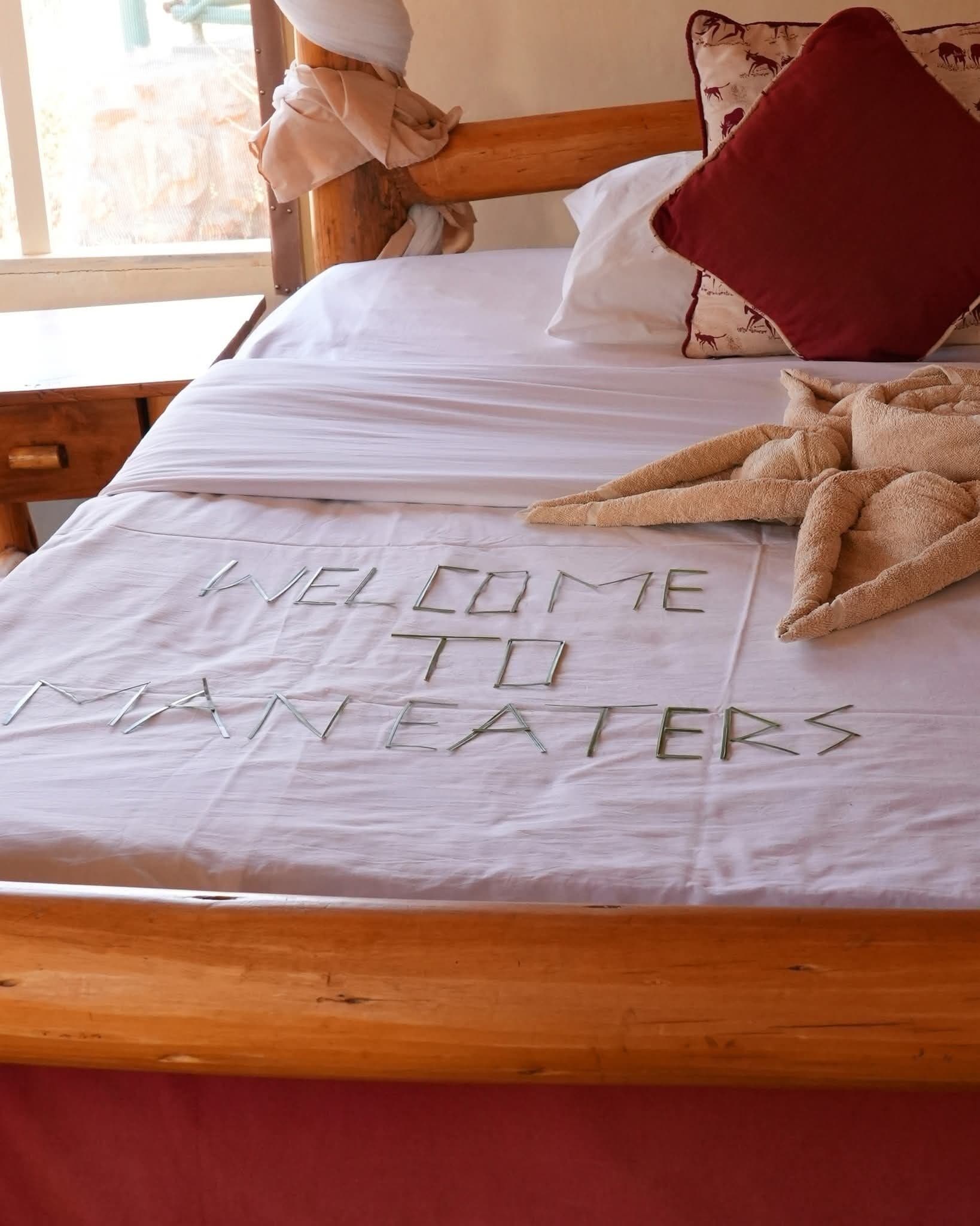 Una cama con sábana blanca y un mensaje escrito con letras de metal.