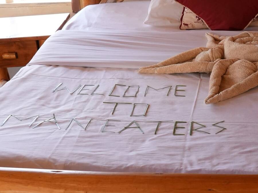 Una cama con sábana blanca y un mensaje escrito con letras de metal.