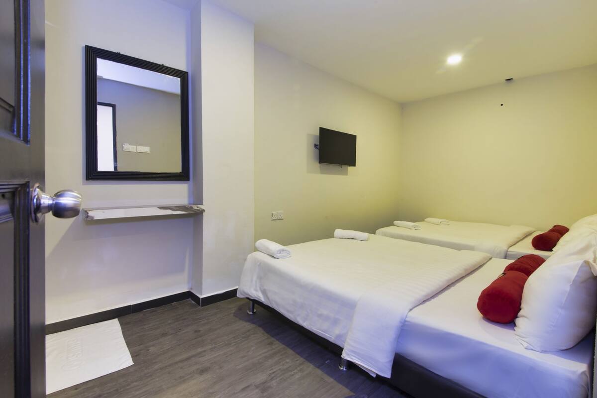 A hotel room with two beds, a flat-screen TV, a mirror, and a door with a handle.