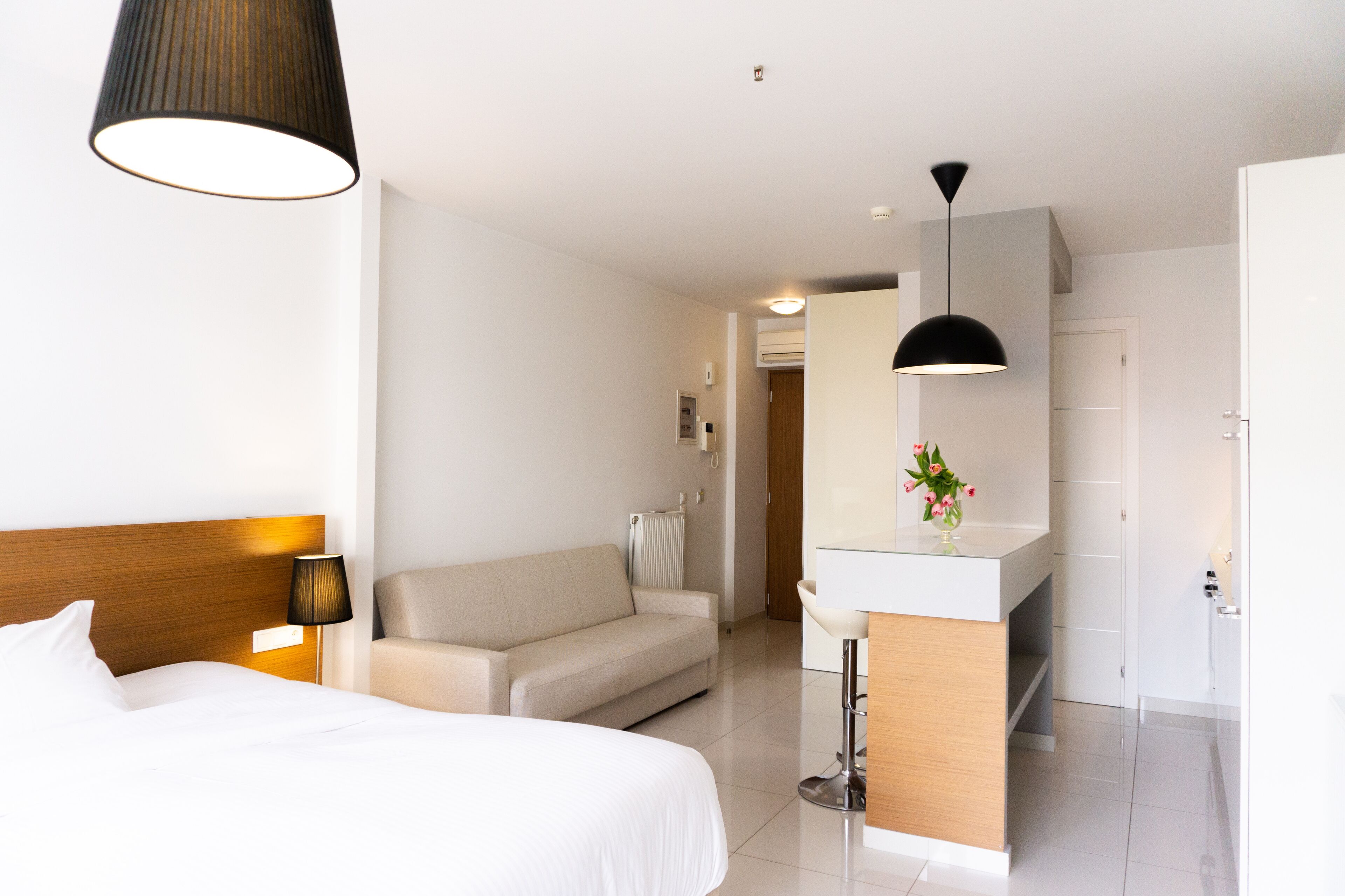 Ett hotellrum med en säng, en soffa, ett skrivbord med en spegel och ett litet badrum.