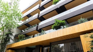 Un edificio moderno de varios pisos con balcones, ventanas amplias y plantas exteriores.