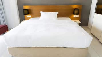 A modern hotel room with a large bed, two bedside lamps, and a wooden headboard.