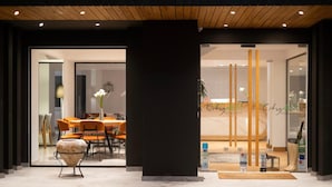 Entrada de hotel con diseño moderno, que incluye una recepción y una zona de estar con sillas naranja.