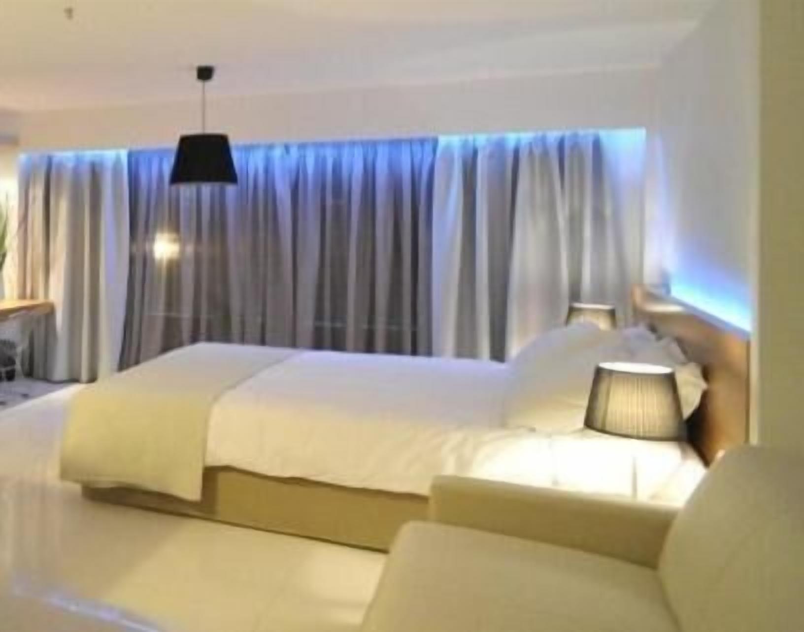 A hotel room with a bed, a bedside table, and a lamp.