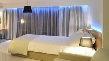 A hotel room with a bed, a bedside table, and a lamp.
