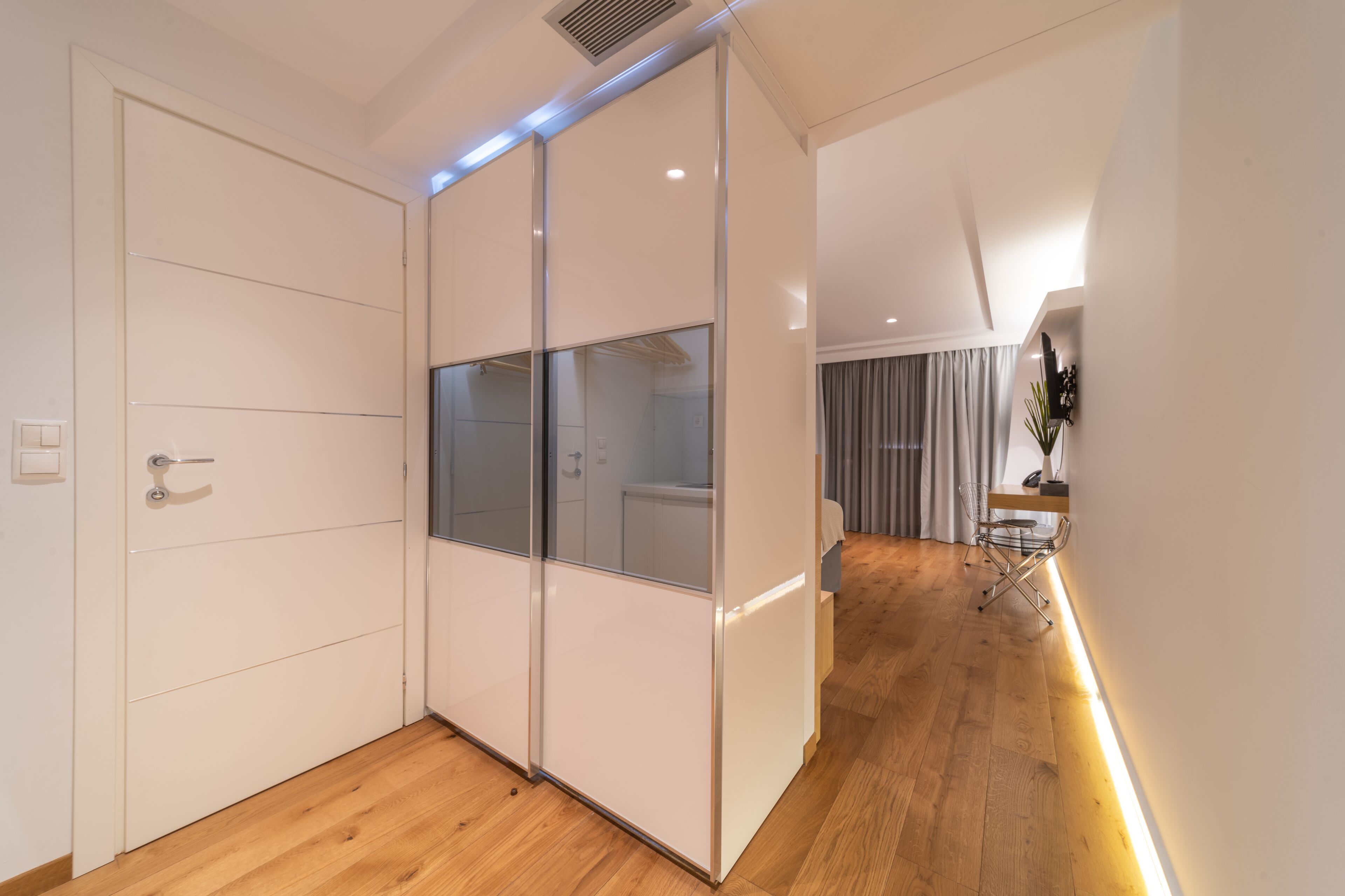 A modern room with a sliding door, wooden flooring, and a desk with a chair.