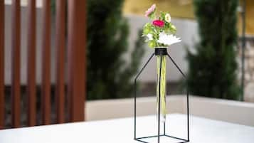 Un florero de vidrio transparente con flores sobre una mesa blanca.