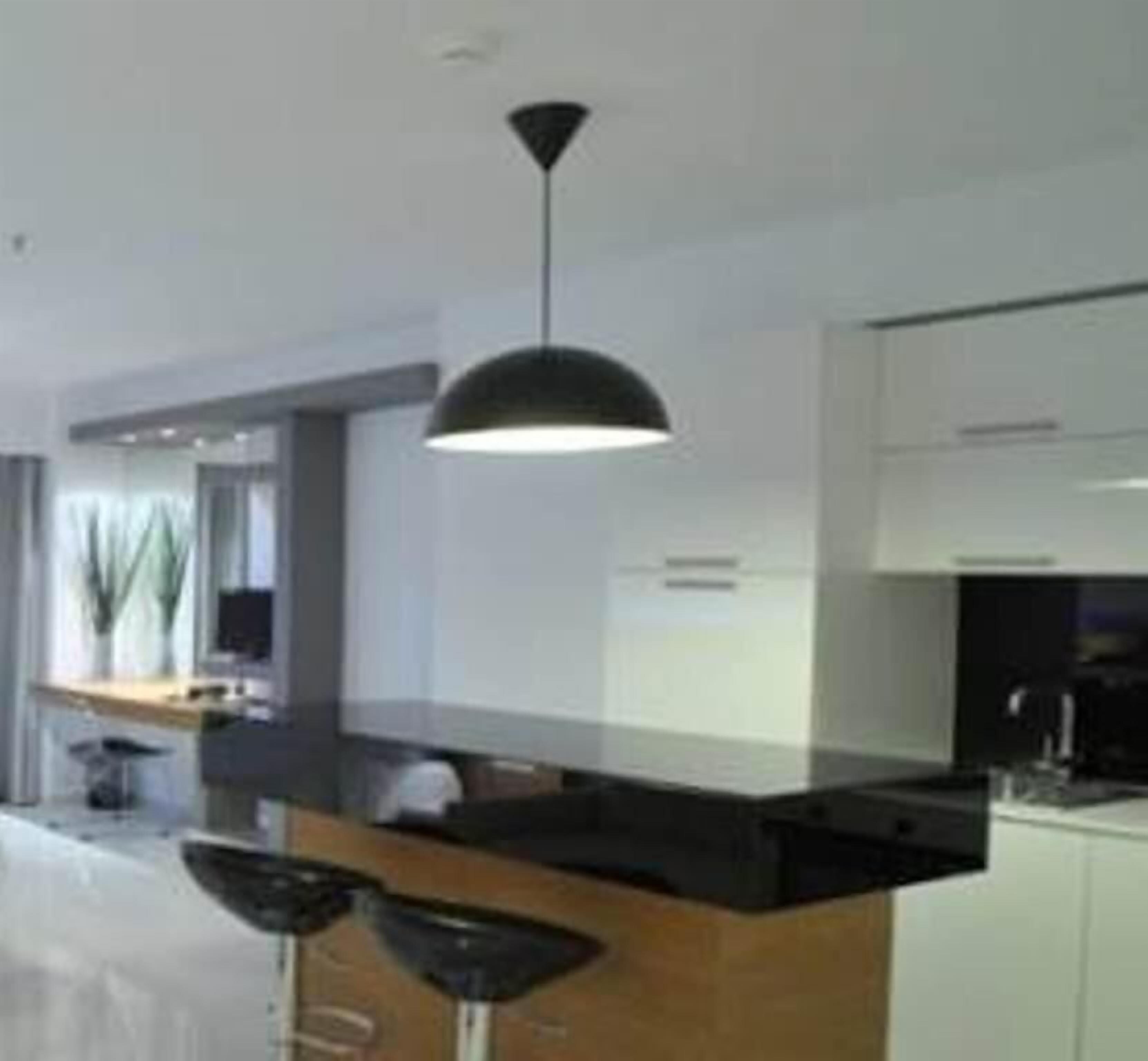 A modern kitchen with a black island, pendant lighting, and a view of the dining area.