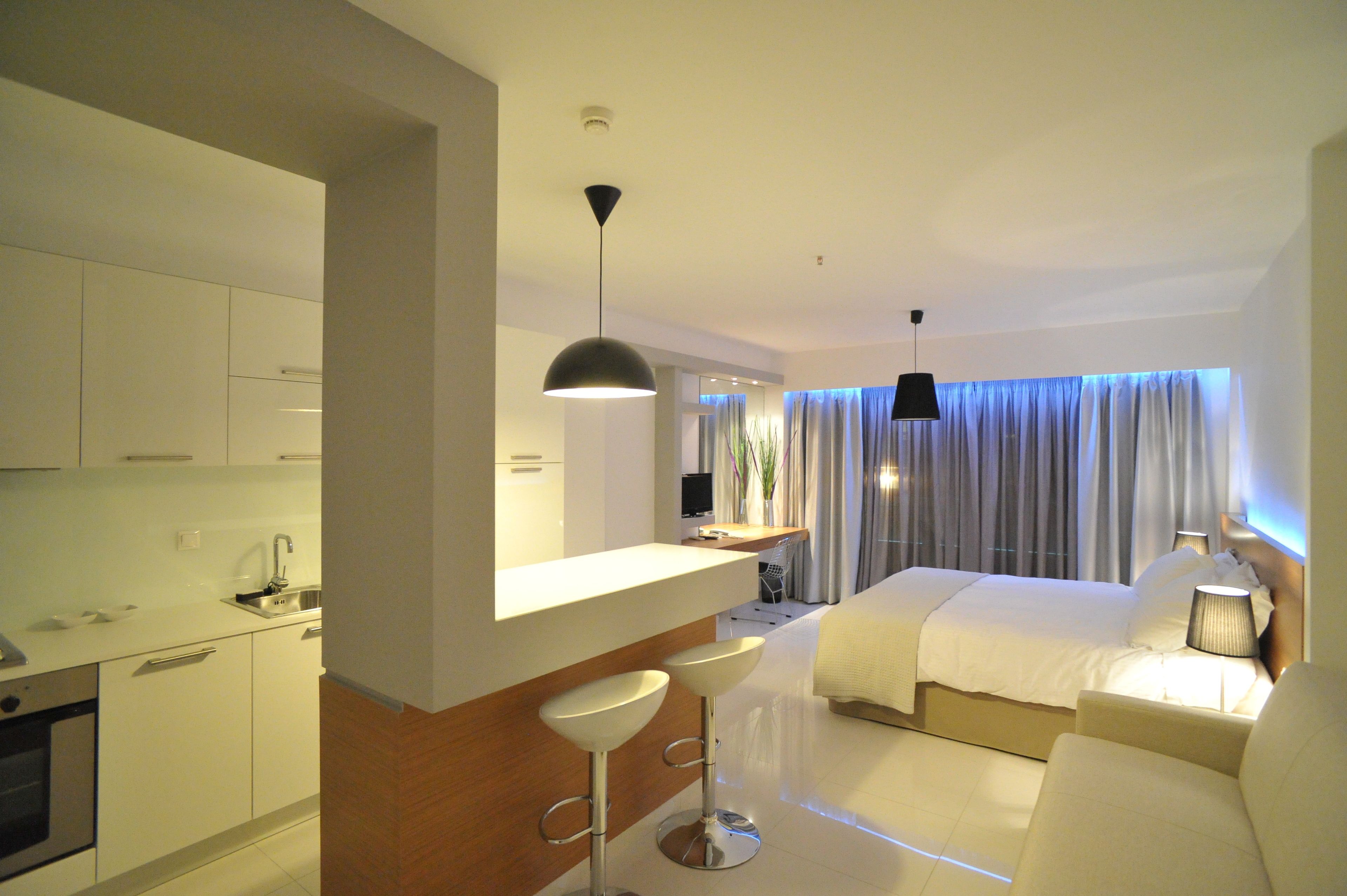 Ein modernes Hotelzimmer mit Küchenzeile, einem großen Bett, einer Sitzecke mit Sofa und einem Essbereich mit Barhocker.