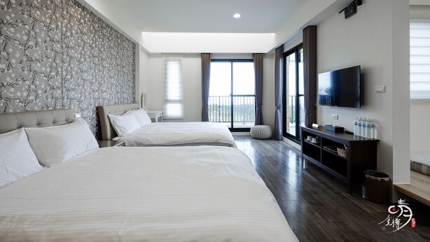 Une chambre d’hôtel moderne avec deux lits, une grande fenêtre avec des rideaux, un téléviseur à écran plat et un plancher en bois.