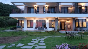 Une maison moderne à deux étages dotée d’un patio couvert, d’un chemin en pierre et d’un espace de détente extérieur.