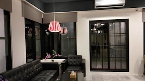 Un salon moderne avec un canapé en cuir noir, une table basse en verre et des suspensions à motifs rayés.