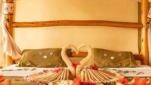 Una cama con dosel, almohadas con forma de cisne y adornos florales.