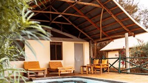 Zona de piscina con un espacio de estar techado, una piscina y un edificio con tejado inclinado.