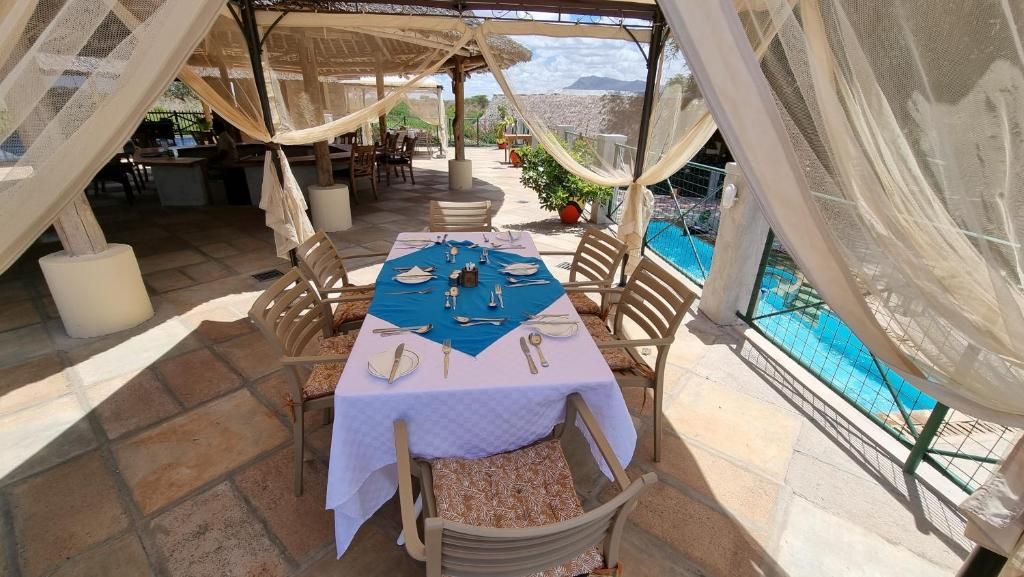 An outdoor dining area with a table set for two, overlooking a pool and a mountainous landscape.