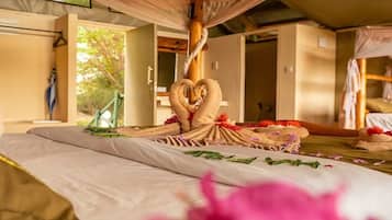 A room with a bed, a wooden ceiling, and a window.