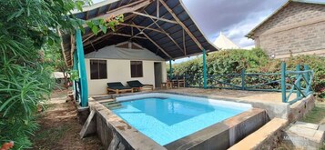 Una piscina con zona de estar cubierta y sillones de descanso.