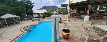 Una piscina con sillas de descanso y una zona de estar cubierta.
