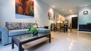 A modern living room with a sofa, a coffee table with a plant, and a dining area with chairs and a table. - Onyx White Pearl Villa (Rawai)
