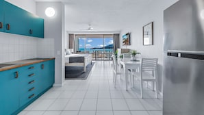 A modern kitchen with teal cabinets, a white countertop, and a stainless steel refrigerator. - Ocean Views 49A (Airlie Beach)