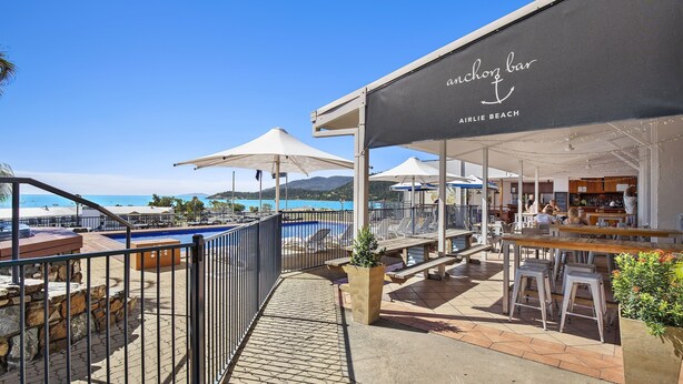 A beachside bar with outdoor seating and a pool view. - Ocean Views 49A (Airlie Beach)