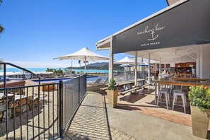 Un bar situé en bord de plage, avec une terrasse et une vue sur la piscine.