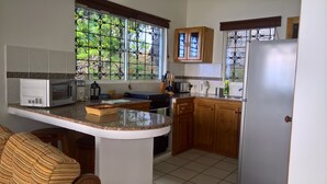 Una cocina con una isla central, microondas, estufa y refrigerador.