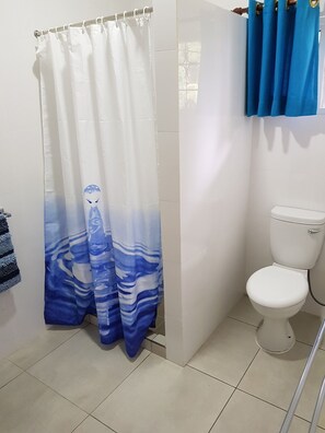 A bathroom with a white toilet, a blue and white shower curtain, and a blue towel hanging on the wall.