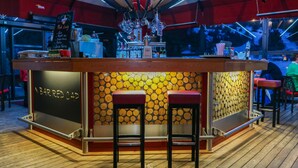 Un espace bar avec des tabourets, un menu écrit à la craie et un mur en bois orné de motifs circulaires.