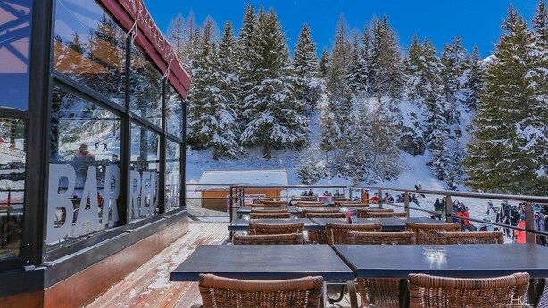 Un bar doté d’une terrasse offrant une vue sur un paysage montagneux enneigé.
