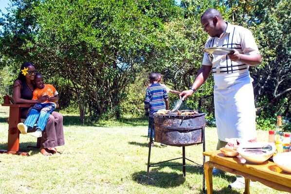 Una familia al aire libre con una parrilla para barbacoa.