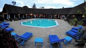 Un área de piscina con sillas reclinables azules y un edificio al fondo.