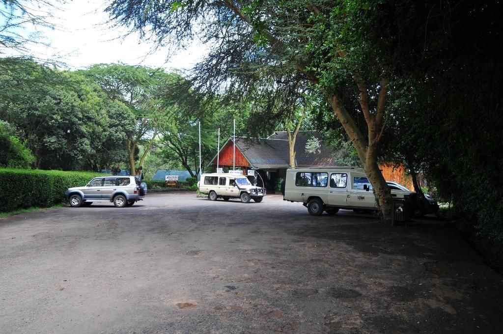 A parking area with three vehicles parked near a building with a red roof.