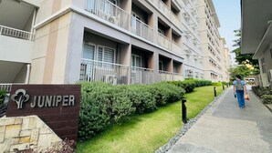 Un edificio residencial de varios pisos con balcones, un césped cuidado y un cielo despejado.