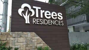 Letrero de Trees Residences con un diseño moderno y un muro de piedra en la base.