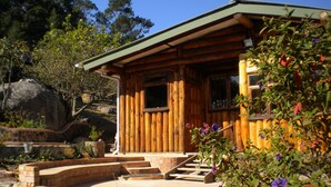 Une cabane en bois avec des fondations en pierre, une terrasse en bois et un mur en pierre.