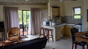 Un grand espace de vie comprenant un canapé, une table à manger et un coin cuisine équipé d’une cuisinière et d’un four à micro-ondes.