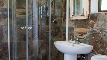 A bathroom with a glass-enclosed shower, a pedestal sink, and a toilet.