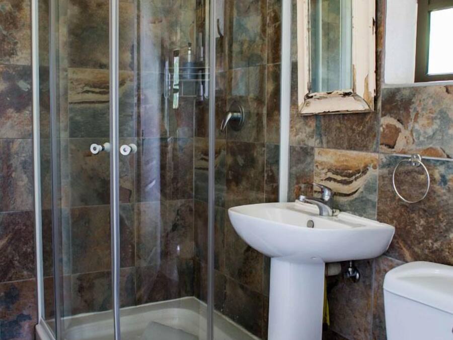 A bathroom with a glass-enclosed shower, a pedestal sink, and a toilet.