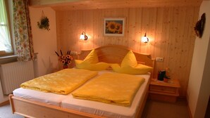 A wooden-paneled bedroom with a bed, two bedside lamps, a nightstand, and a window with curtains. - Ferienwohnung Taubensee, 1-2 Personen, 45 qm, Bad + Dusche/WC, Südbalkon, TV, 1 Schlafzimmer, Nichtraucher (Ramsau bei Berchtesgaden)